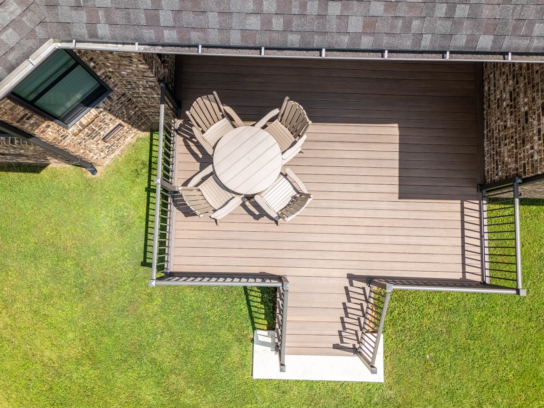 Composite deck stairs and railing leading toward a scenic lake surrounded by trees