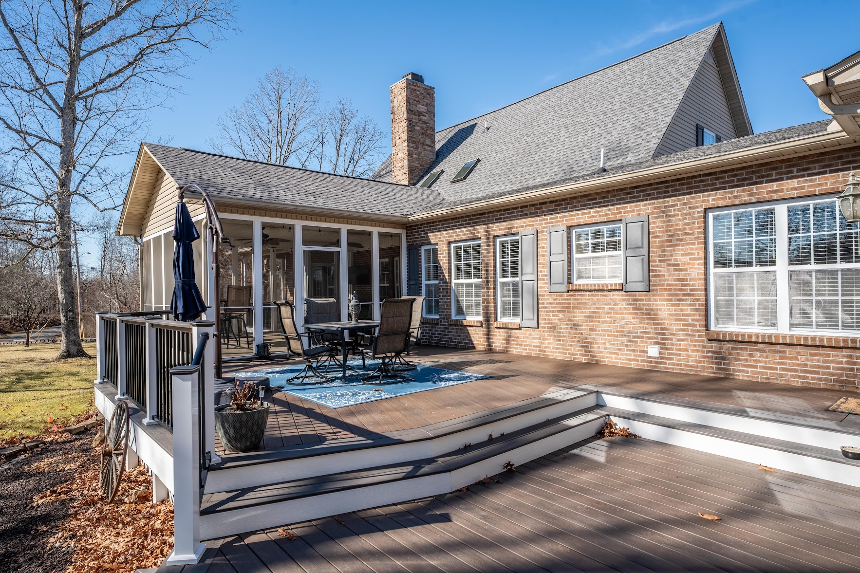 Outdoor patio with composite deck, furniture, and grill area against a brick house